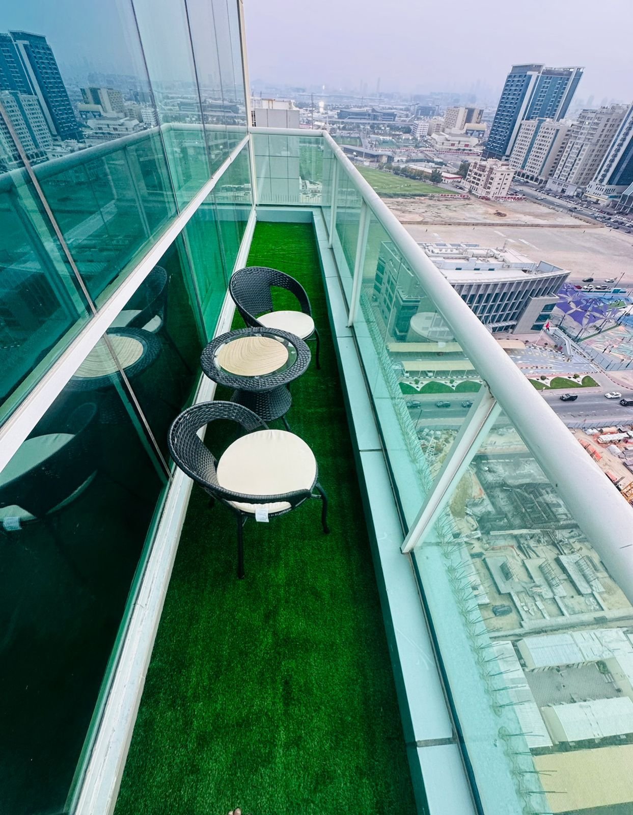 Artificial grass installed on a Dubai balcony with rattan seating